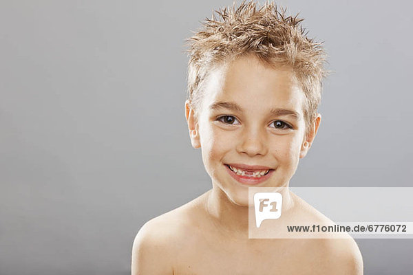 Studio portrait of toothless boy (8-9) smiling