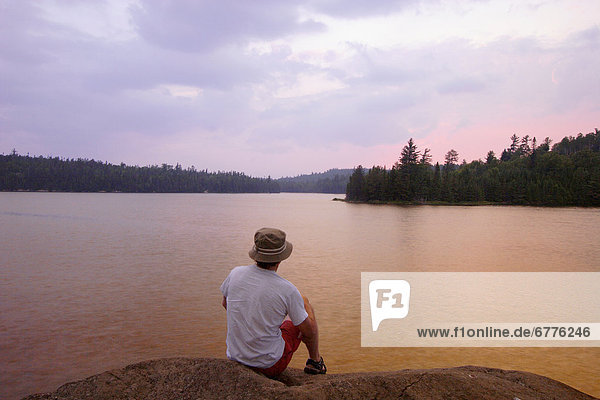 Man sitting on Rocks at Sunset  Lake Temagami near sunset  Temagami  Ontario