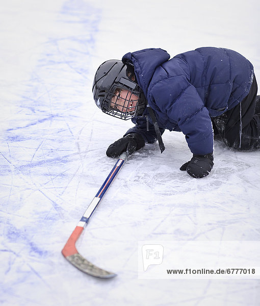 Young ice hockey player laughing after falling on the ice  Winnipeg  Manitoba  Canada