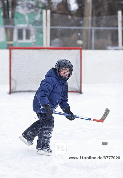 Young boy playing ice hockey on an outdoor rink  Winnipeg  Manitoba  Canada