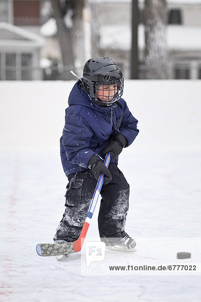 Young boy playing ice hockey on an outdoor rink  Winnipeg  Manitoba  Canada