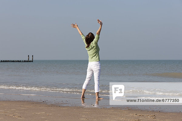 Woman on beach with arms raised