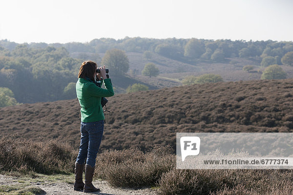The Netherlands  Veluwezoom  Posbank  Woman in countryside looking through binoculars