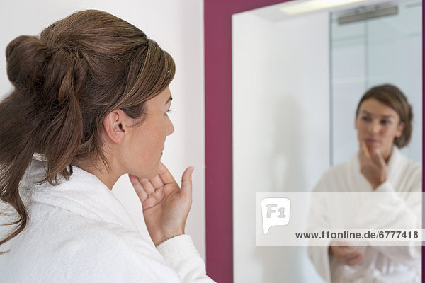 Woman looking in Badezimmerspiegel