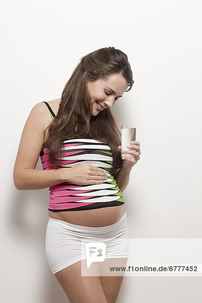 Portrait of pregnant woman holding glass of water  studio shot