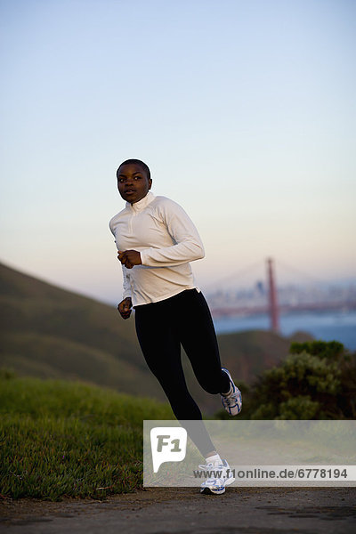 USA  California  San Francisco  Woman jogging  Golden Gate Bridge in background