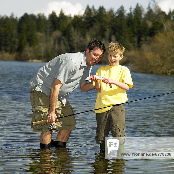 Man and boy standing in lake  boy holding fish  Victoria  British Columbia
