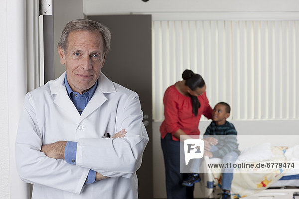 Portrait of male doctor with patients in background