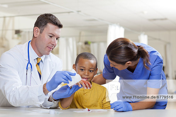 Doctors applying bandage on boy's (4-5) hand