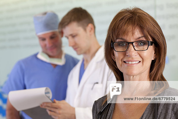 Portrait of female doctor  male doctor and surgeon in background