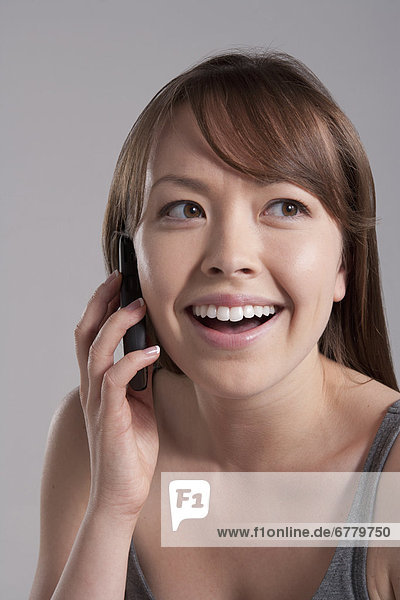 Portrait of young smiling woman using mobile phone  studio shot