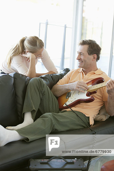 Mature man playing guitar while woman listening
