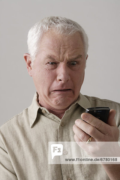 Portrait of senior man with mobile phone  studio shot