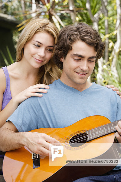 Young couple in park  man playing guitar