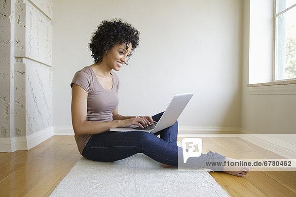 Young woman sitting in room using laptop