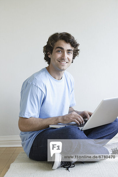 Young man sitting in room using laptop