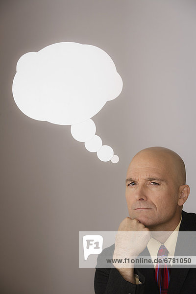 Studio shot of pensive business man with speech bubble above head