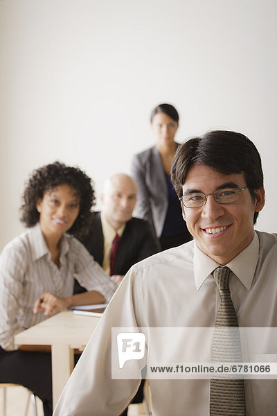 Smiling businessman looking at camera  business team in background