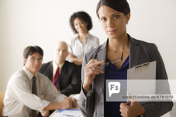 Young businesswoman looking at camera  business team in background