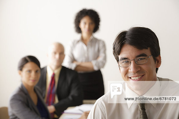 Young businessman looking at camera  business team in background