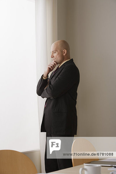 Thoughtful businessman standing in board room