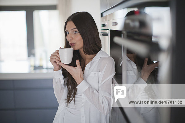 Young woman enjoying coffee in domestic kitchen