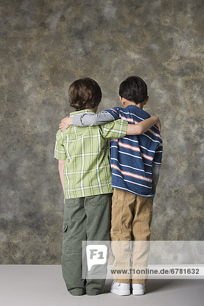 Rear view of two boys (6-7  8-9) standing together  studio shot