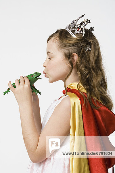 Girl (8-9) dressed as princess kissing frog  studio shot