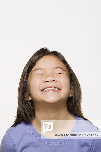 Portrait of smiling girl (8-9) with eyes closed  studio shot