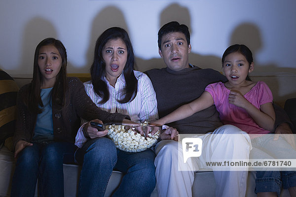 Parents with two daughters (8-9  10-11) watching tv on sofa