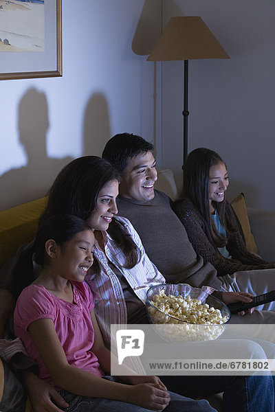 Family with two children (8-9  10-11) watching tv on sofa