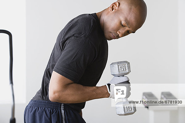 Junger Mann anhebende Gewichte im Fitness-Studio