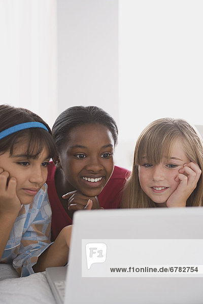 Portrait of three girls (10-11) using laptop