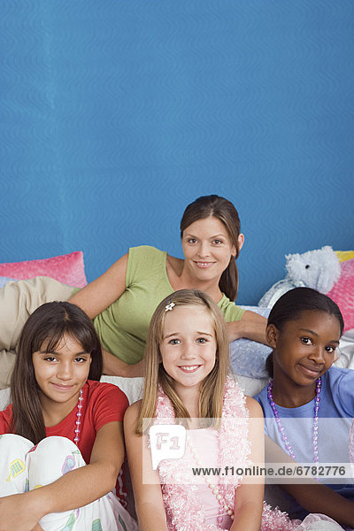 Portrait of woman and three girls (10-11) at slumber party