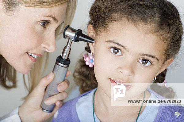 Doctor examining girl's (10-11) ear