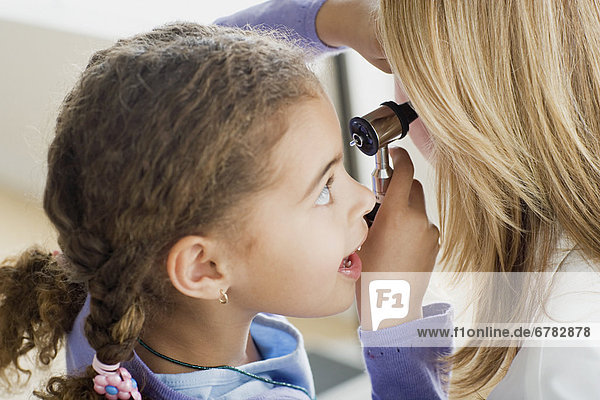 Girl (10-11) examining doctor's ear with otoscope