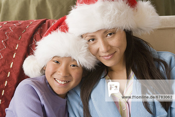 Portrait of mother and daughter (10-11) wearing Santa hats