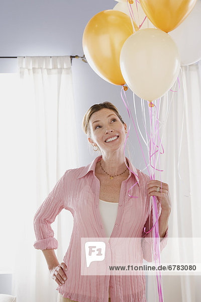 Smiling mature woman holding balloons