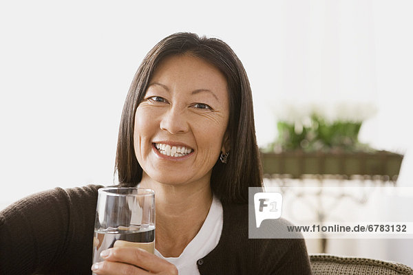 Portrait of smiling woman holding glass of water