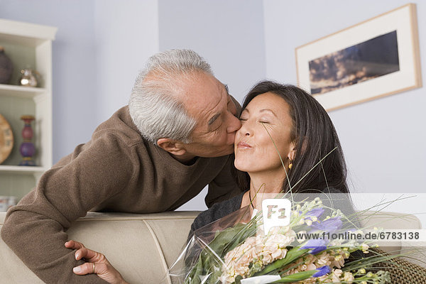 Woman receiving kiss and flowers from husband