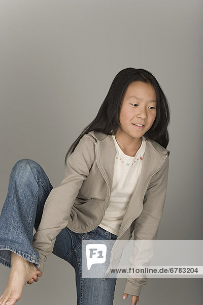 Studio portrait of teen (16-17) girl standing on one leg