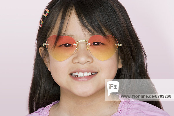 Studio portrait of girl wearing heart-shaped glasses