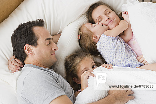 Family with two children chilling in bed