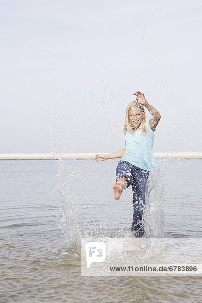 Girl kicking water at beach