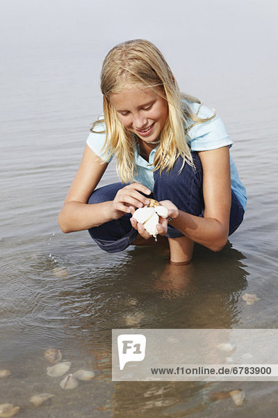 Girl looking for shells in shallow water