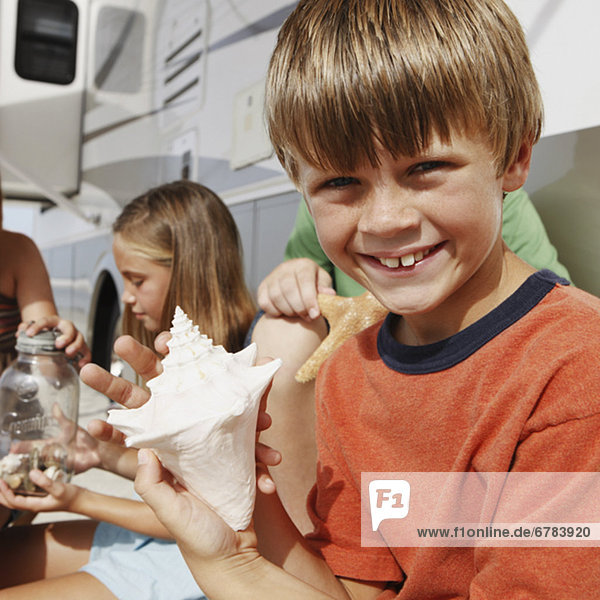 Children looking at seashell collection by motor home