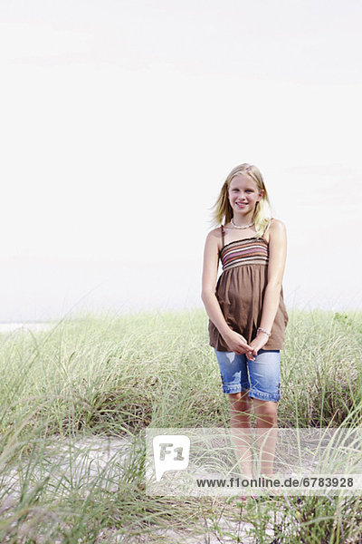 Girl standing on grassy sand dune