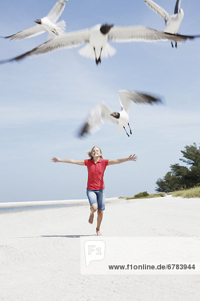 Girl chasing birds on beach