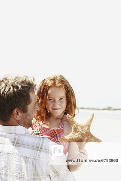 Father carrying daughter and starfish