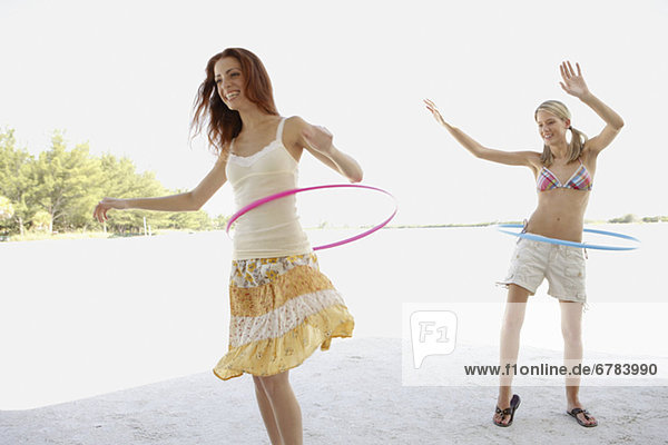 Young women hula hooping on beach